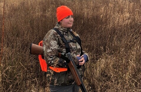 a woman hunter stands in a field