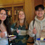 3 students smiling while holding plates with slices of cake. 