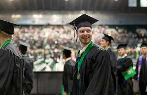 UND student smiling and looking off in the distance at winter commencement ceremony.