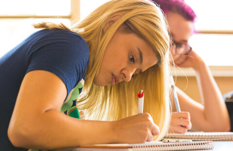 Student in CNM's Liberal Arts program focuses on completing a paper assignment on their desk