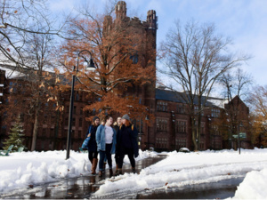 Smiling students walk across a snowy campus.