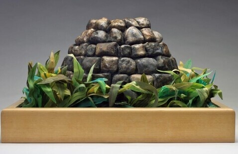 a wooden box with fake plants around a stone dome