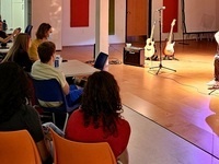guitarist playing on stage of C4C: The Understory with audience looking on