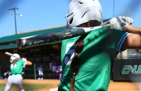 Mean Green Softball batter in the batter's box in the foreground, and a Mean Green Softball batter at the plate in the background.