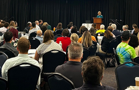 Person at a podium speaking to an audience