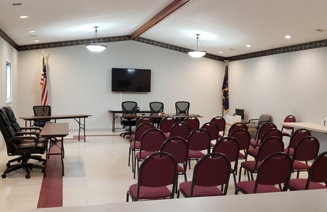 Photo shows the inside of the council chamber. Several rows of straight back chairs the council's table.