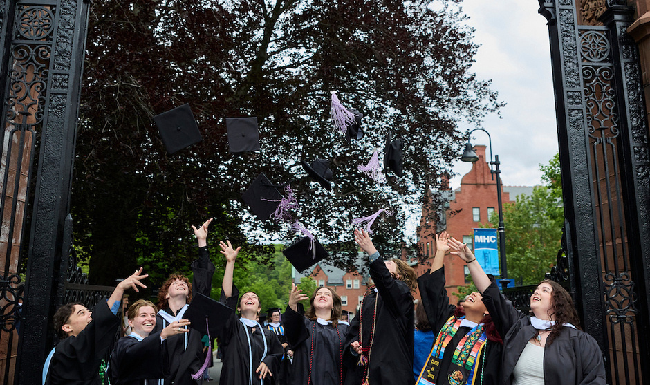 New graduates toss their caps in the air by the Gates.