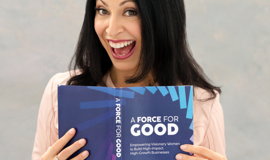 woman with dark hair holds a book with a blue cover.