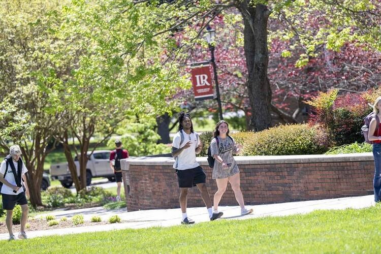 Two students walking along sidewalk in the springtime