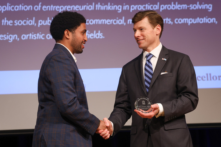 Chancellor Lee H. Roberts shakes the hand of a student presenting them with an award.