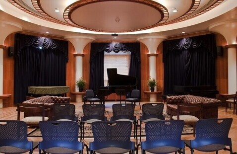 chairs facing a piano lined up in a small room.