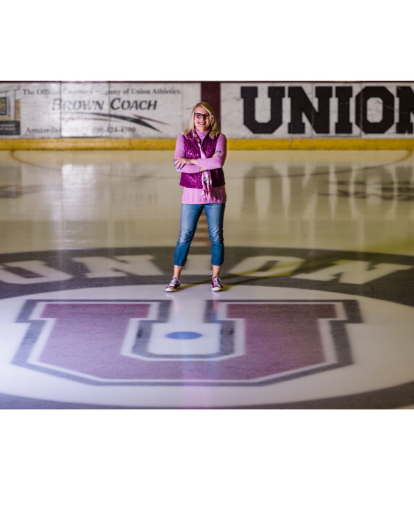 Brianne stands on an ice rink and smiles at the camera. 