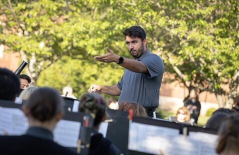 Student conductor leads musicians during concert on Grace Chapel lawn