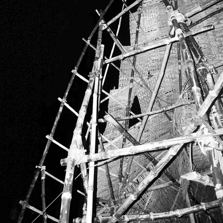 black and white photo of a bamboo and thatch structure