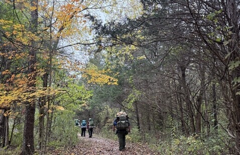 hiker on trail with fall leaves