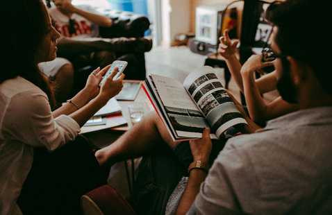 group of adults with books, magazines, and phones