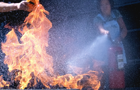 Student using a fire extinguisher on fire during a training event