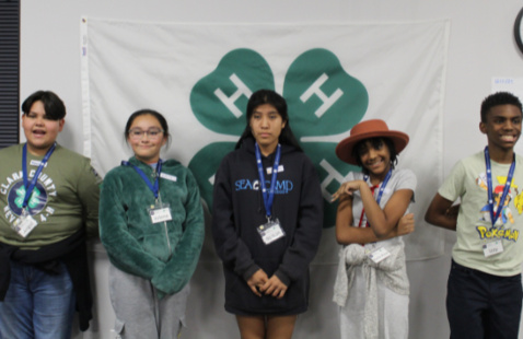 4 kids standing in front of a 4-H flag