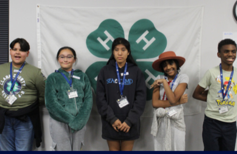 4 kids standing in front of a 4-H flag