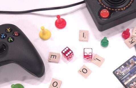 a black game controller, dice, and several scrabble pieces scattered across a table