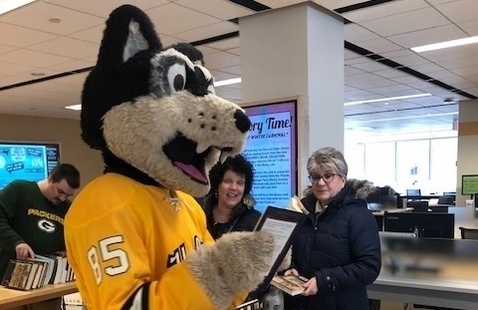 MTU Blizzard mascot reading a book at the book sale