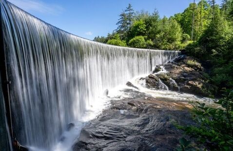 A curved curtain of water flowing over the perfectly level dam that forms Lake Sequoyah blocking the Cullasaja River, Highlands, North Carolina