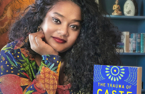 Thenmozhi Soundararajan stands next to her book, "The Trauma of Caste".
