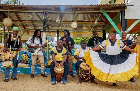 A group of musicians standing in front of an awning holding various instruments.