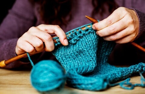 a pair of hands knitting with yarn and needles