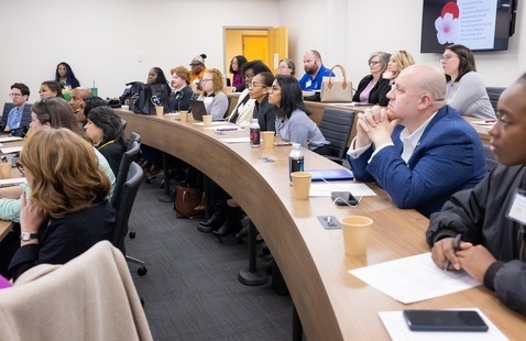Conference attendees listening to a presentation in a tiered classroom.