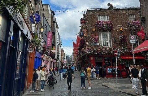 street in Dublin, with buildings on each side and people throughout, with a blue sky in the background