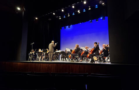 Appears to be a conductor leading performers on stage.