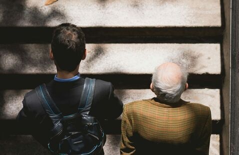 Overhead, back-facing view of a man walking next to an older man 