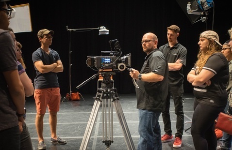 a group of students gathered around a film camera
