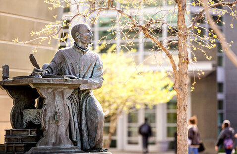 Statute of St. Ignatius writing at his desk
