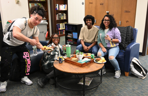 Four students gather inside the Kearns Center living room.