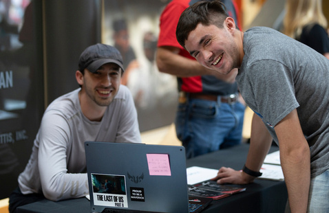 Two men smiling in front of laptop