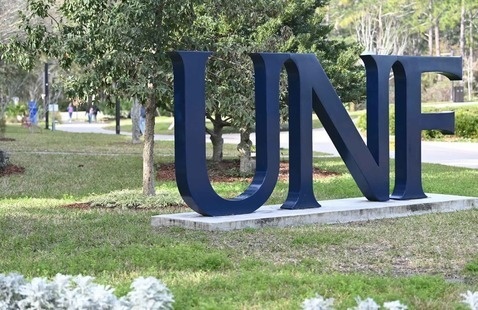 Large blue UNF letters standing upright on grass