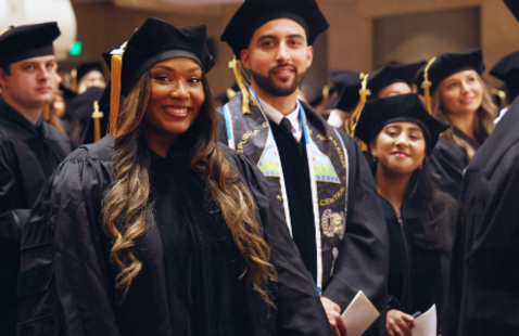 Dental students in graduation regalia smiling for photo at DMD Commencement ceremony