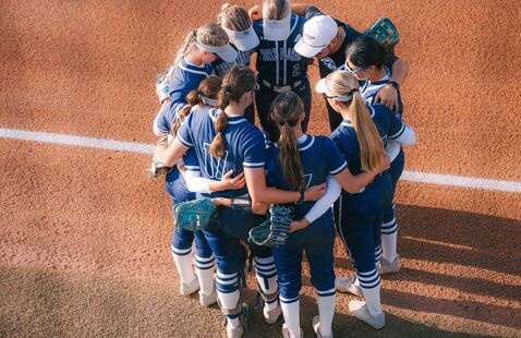 Softball players in huddle on field