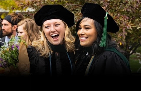 Two female graduates in regalia smiling