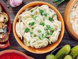 Image of table with Russian dishes - sauerkraut, pickles, blini, mushrooms.