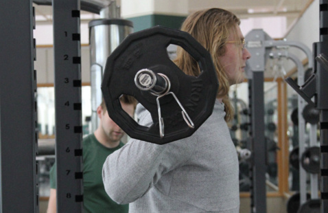 a man holding a bench press bar behind his head.