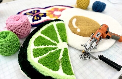 A work surface layered with colorful rugs and yarn. 