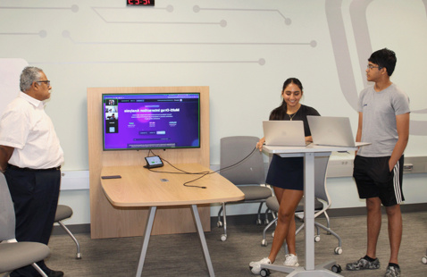 Two students present a project to a professor in the FNBO Code Studio at UNO's Peter Kiewit Institute.