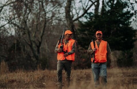 Two hunters walking through a field