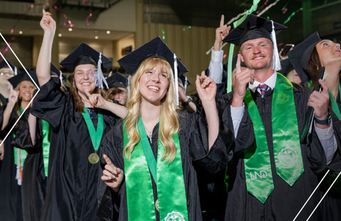 Students wearing caps and gowns celebrating graduation