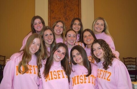 Group of 11 women in pink "misfitz" sweatshirts.