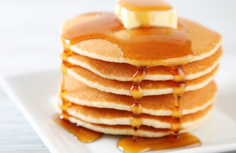 Stack of pancakes on plate with butter and syrup melting over the top