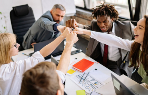 group of people sitting at a table fist bumping